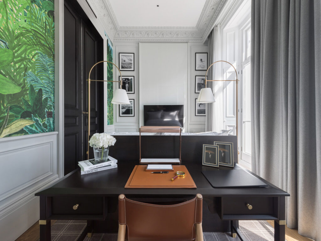 a home office with a black desk and brown leather chair
