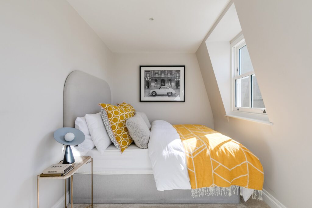 A bed with pillows and a picture on the wall