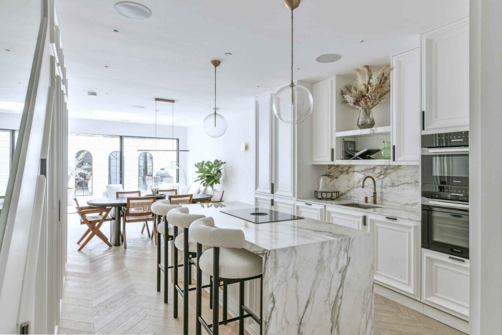 A kitchen with a marble island and a dining table