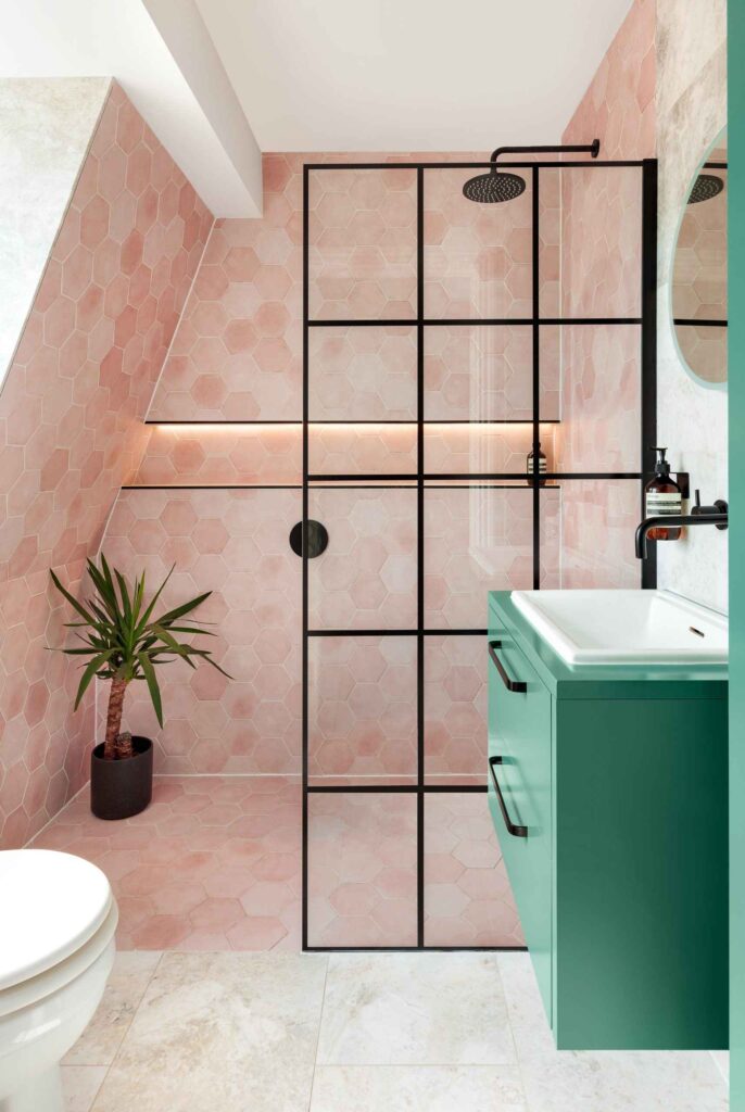 A bathroom with pink tiles and a green sink