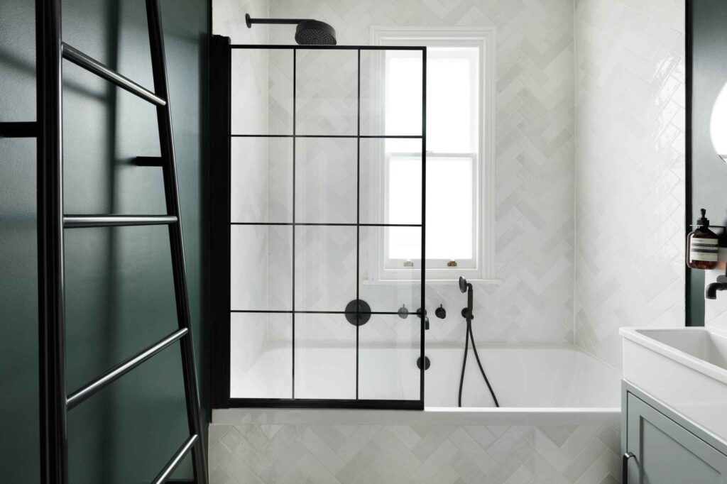 A bathtub with a glass door with black details