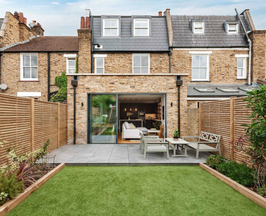 A red brick house with a backyard patio and grass
