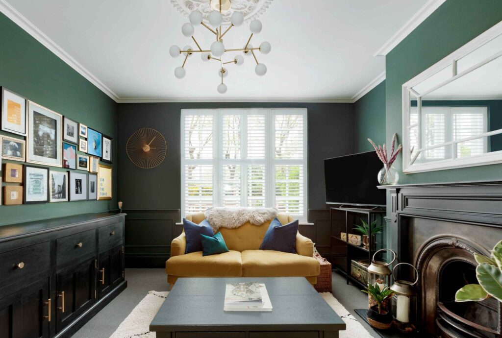 A living room with green walls, a yellow sofa and a fireplace